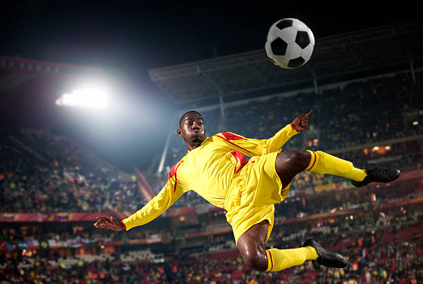 Soccer player kicking the ball, in mid air
